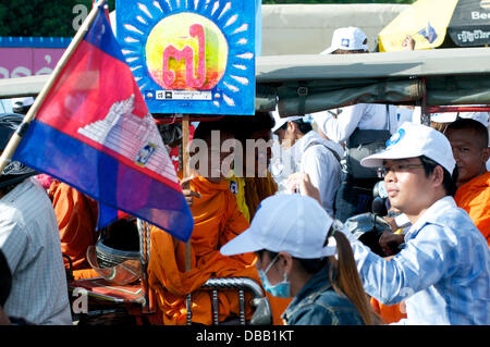 Phnom Penh Cambogia in luglio. 26th, 2013. Sam Rainsy fautore di un monaco buddista, tenendo dipinto luminosamente segno, Cambogiano sventola in primo piano. Sam Rainsy è stato in auto-esilio in Francia dal 2009. Egli era stato concesso un regale perdono dal Re di Cambogia e restituito alla Cambogia su luglio 19th, 2013. Credito: Kraig Lieb/Alamy Live News Foto Stock