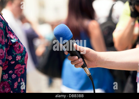 Un giornalista sta facendo un colloquio con un microfono Foto Stock