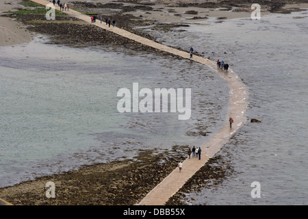 Pedoni attraversare il sentiero a San Michele di montaggio della Cornovaglia come la marea entra in Foto Stock