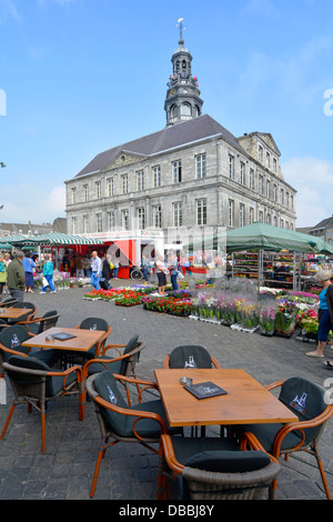 Tavoli da bar e caffè di Maastricht all'aperto nella piazza del mercato con bancarelle che vendono fiori e piante e lo storico edificio del municipio nel Limburgo Paesi Bassi UE Foto Stock