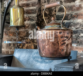 Bollitore di rame appeso sopra il vecchio stufa. Foto Stock