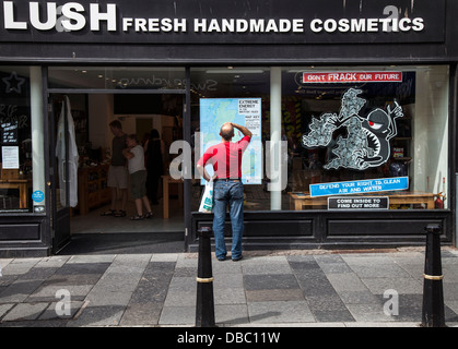 Uomo che guarda la mappa del Regno Unito in lussureggianti cosmetici Window negozi ed edifici di Inverness High Street, Scotland, Regno Unito Foto Stock