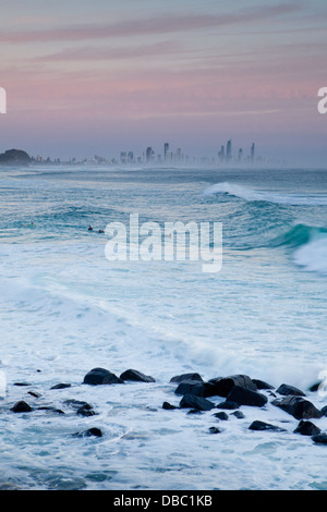 La mattina presto surfisti a Burley teste con skyline di Surfers Paradise in background. La Gold Coast, Queensland, Australia Foto Stock