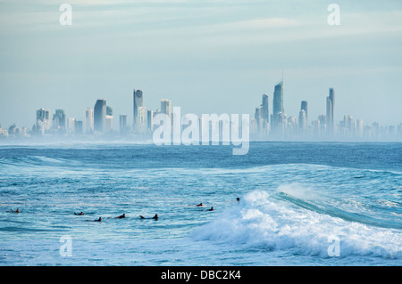 Surfisti in mattinata si gonfiano con Surfers Paradise skyline in background. Burleigh capi, Gold Coast, Queensland, Australia Foto Stock