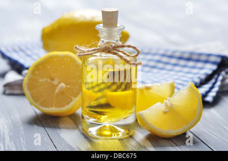 Olio di limone in una bottiglia di vetro con fresco лемон он sfondo di legno Foto Stock