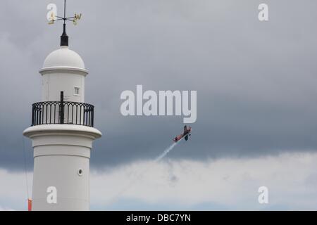 Sunderland, Regno Unito. Il 28 luglio 2013. Una folla di persone godono di spettacoli del venticinquesimo Airshow di Sunderland. Una delle lame 300 Extra velivolo vola oltre il faro. Credito: Ken Meade/Alamy Live News Foto Stock