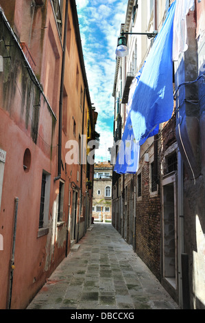 Piccola strada con lenzuola blu appese ad asciugare il giorno di sole fuori case a Venezia, Venezia, Veneto, Italia, Europa Foto Stock