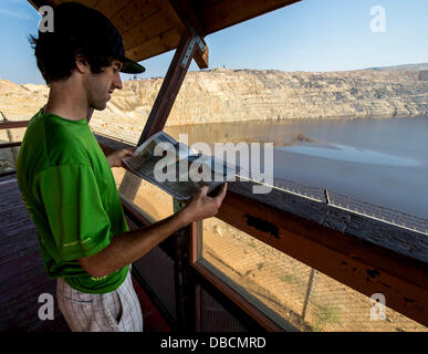 Butte, Montana, USA. 28 Luglio, 2013. Paolo MAYES legge fino sul soggetto come egli si trova sulla piattaforma di osservazione della Berkeley Pit, un'agenzia per la Protezione Ambientale Superfund site che la città di Butte è stata marketing come due dollari ammissione di attrazione turistica. In produzione dal 1955 al 1982, l'open peccato miniere di rame a Berkeley ha prodotto circa 320 milioni di tonnellate di minerale e di oltre 700 milioni di tonnellate di rifiuti di roccia, compresi metalli tossici come il cadmio e arsenico. Foto Stock