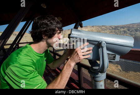 Butte, Montana, USA. 28 Luglio, 2013. Paolo MAYES tenta una per pagare il telescopio ma trova il coin slot è bloccata sulla piattaforma di osservazione della Berkeley Pit, un'agenzia per la Protezione Ambientale Superfund site che la città di Butte è stata marketing come due dollari ammissione di attrazione turistica. In produzione dal 1955 al 1982, l'open peccato miniere di rame a Berkeley ha prodotto circa 320 milioni di tonnellate di minerale e di oltre 700 milioni di tonnellate di rifiuti di roccia, compresi metalli tossici come il cadmio e arsenico. Foto Stock