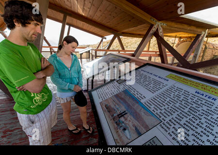 Butte, Montana, USA. 28 Luglio, 2013. Paolo MAYES e LIZ O'NEILL leggere il materiale fornito sulla piattaforma di osservazione della Berkeley Pit, un'agenzia per la Protezione Ambientale Superfund site che la città di Butte è stata marketing come due dollari ammissione di attrazione turistica. In produzione dal 1955 al 1982, l'open peccato miniere di rame a Berkeley ha prodotto circa 320 milioni di tonnellate di minerale e di oltre 700 milioni di tonnellate di rifiuti di roccia, compresi metalli tossici come il cadmio e arsenico. Foto Stock