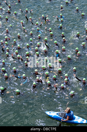 I nuotatori ondano agli spettatori mentre una canoa di sicurezza mantiene un occhio vigile alla linea di partenza Foto Stock