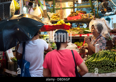 Donna che indossa un sacchetto di plastica sul suo capo in una piovosa Graham Street mercato umido, Isola di Hong Kong Foto Stock