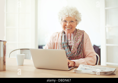 Allegra donna senior utilizzando laptop come ricreazione a casa Foto Stock