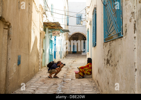 Fotografo scatta una fotografia di una donna musulmana in una strada stretta di Sousse, Tunisia. Foto Stock