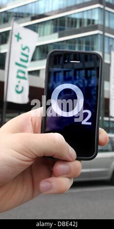 Illustrazione - un'immagine illustrata mostra uno smartphone con il logo della società di telecomunicazioni o2 essendo mantenuto fino di fronte alla sede centrale di E-Plus Gruppo a Duesseldorf in Germania, 29 luglio 2013. Foto Foto Stock