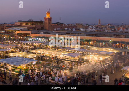 Affacciato sulla alfresco mercato alimentare in Djemaa el Fna al tramonto, con i souk e il minareto della moschea dietro a Marrakech, Marocco Foto Stock