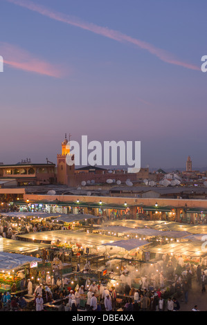 Affacciato sulla alfresco mercato alimentare in Djemaa el Fna al tramonto, con i souk e il minareto della moschea dietro a Marrakech, Marocco Foto Stock