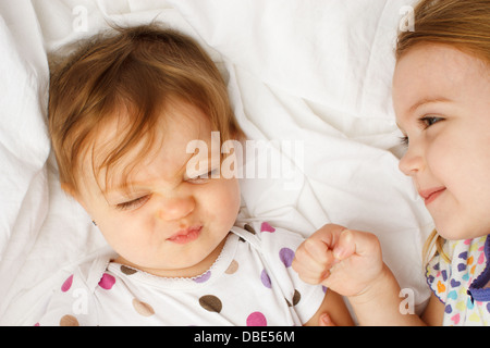 Silly baby in fogli con big sister Foto Stock