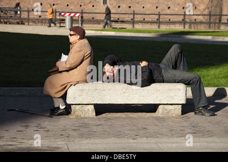 Senior donna in un parco con uomo dorme Foto Stock