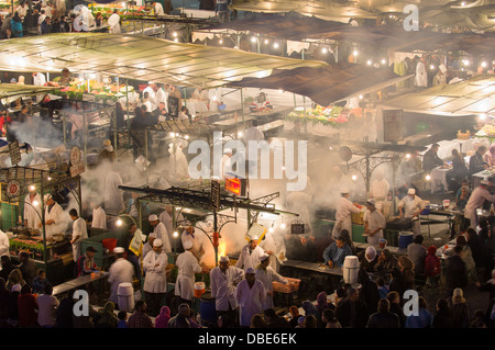 Guarda le bancarelle di occupato del alfresco mercato alimentare in Djemaa el-Fna di notte a Marrakech, Marocco Foto Stock