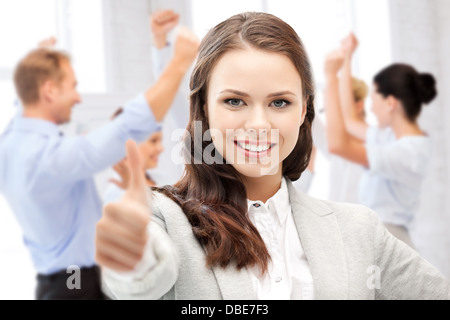 Imprenditrice che mostra i pollici in su in ufficio Foto Stock