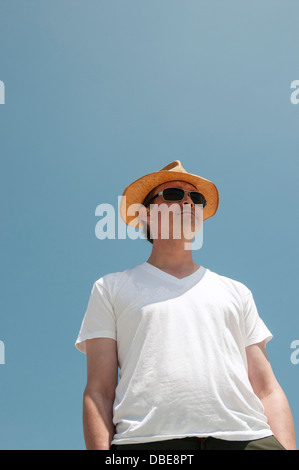 Un uomo in un bianco t shirt indossando un fedora. Foto Stock
