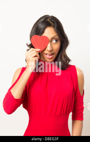 Etnica donna giovane azienda forma di cuore su di un occhio Foto Stock