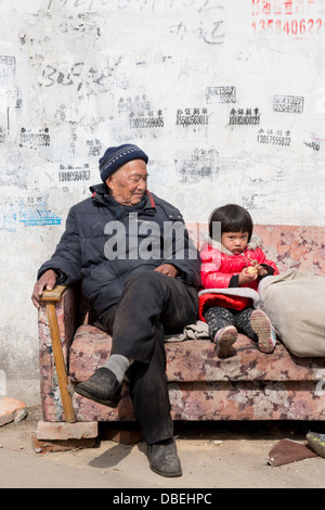 Qijiawan, Nanjing, Cina. Nonno e nipote seduto su un divano in strada. Foto Stock