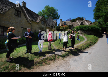 I turisti alla fila di Arlington, iconico riga del xvii secolo Cotswolds cottages in Bibury, Regno Unito Foto Stock