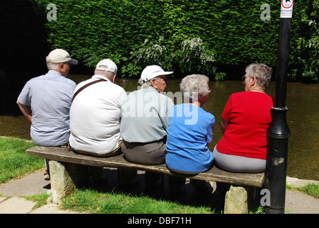 I pensionati sulle rive del Fiume Windrush a Bourton sull'acqua Gloucestershire England Regno Unito Foto Stock