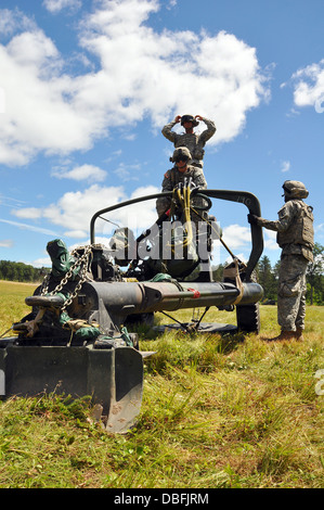 Cannon membri di equipaggio dal 1° Battaglione, centoventesimo artiglieria campo attendono l arrivo di un Black Hawk elicottero dal 1° Battaglione, 147th reggimento di aviazione per imbracare-caricare il 105-mm obice per il trasporto come parte di un combinato di bracci di Formazione Missionaria luglio Foto Stock