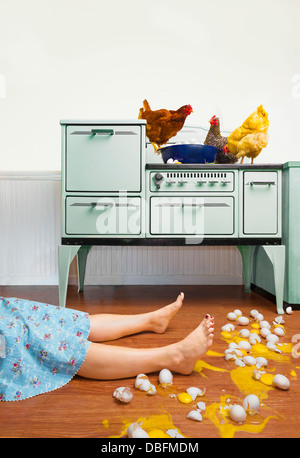 La donna caucasica sul pavimento della cucina con uova rotte Foto Stock