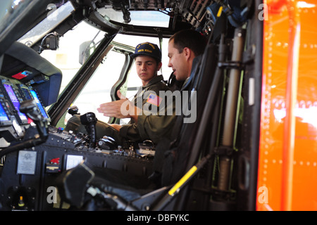 Lt. Kevin inverni, una stazione di aria Kodiak MH-60 Jayhawk pilota di elicottero, spiega il cockpit del Jayhawk a Braeden Hahn, un residente del New Jersey e la prospettiva di Coast Guard pilota di elicottero, alla stazione di aria di Kodiak, Alaska, 24 luglio 2013. Baead Foto Stock