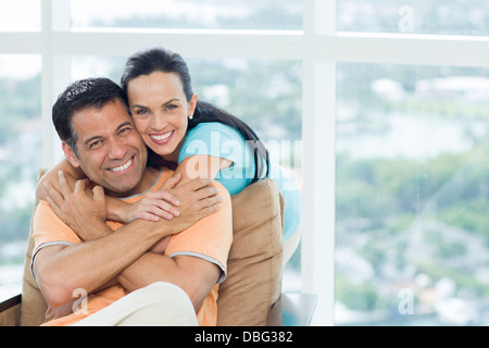 Coppia ispanica abbracciando in poltrona Foto Stock