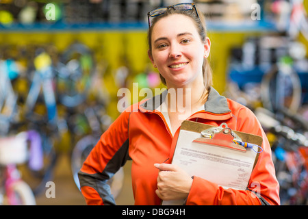 La donna caucasica con appunti nel negozio di biciclette Foto Stock