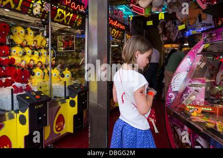 Arcade con gru artiglio macchine di gioco e il bambino guardando coin spintore / Medaglia push gioco a viaggiare luna park / CARNEVALE Foto Stock