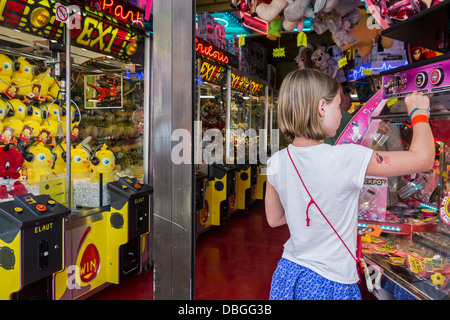 Arcade con gru artiglio macchine da gioco e i bambini a giocare con gettoni spintore / Medaglia push gioco a viaggiare luna park / CARNEVALE Foto Stock