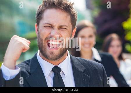 L'uomo maschio imprenditore executive pugno alzato per celebrare il successo il tifo urlando di fronte la sua femmina business i colleghi di squadra Foto Stock