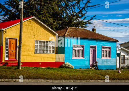 Persona seduta sulla soglia della case vivacemente colorate in vividi Punta Arenas, Cile Foto Stock