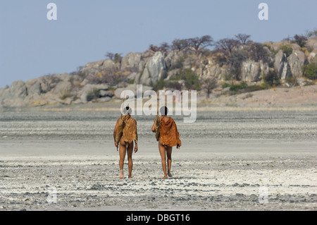 San bushman trackers attraversando a piedi il incrinato pan verso l'antico affioramento di granito di Kubu Island (Lekhubu), Makgadikgadi Pan, Botswana Foto Stock