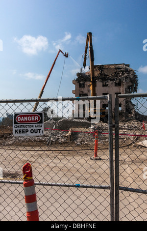 Segnaletica di pericolo sul recinto con la costruzione di demolizione in background tramite escavatore al vecchio ospedale di Eden in Castro Valley, California. Foto Stock