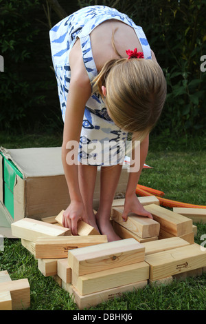 Ragazza che gioca con la costruzione di blocchi in giardino nei mesi estivi Birmingham West Midlands England Foto Stock