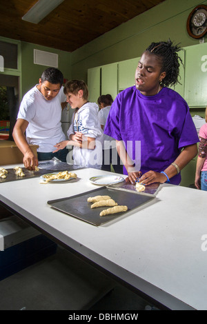 Un cieco di afro-americano di preteen girl produce rotoli da toccare dalla pasta preparati in una cucina e panificazione classe Foto Stock