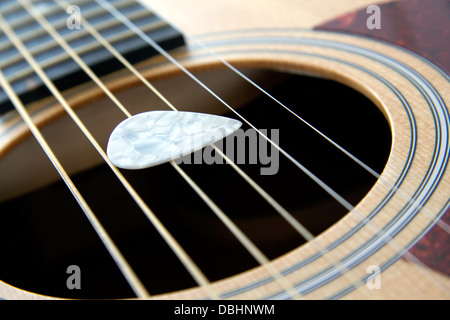 Plettro bianco su una stringa di 6 chitarra acustica Foto Stock