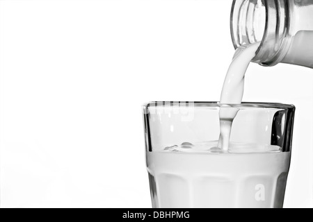 Il latte che viene versato da una bottiglia in un bicchiere Foto Stock