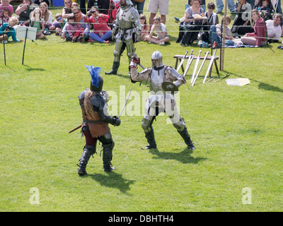 Due cavalieri in armatura in una storica torneo medievale rievocazione dimostrando lotta con la spada a piedi Foto Stock