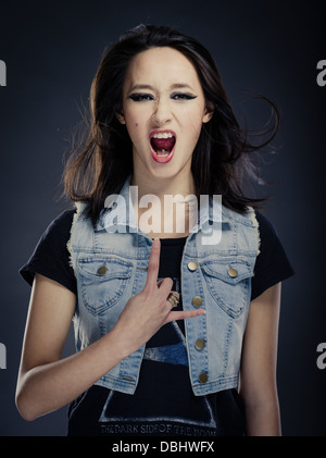 Bella donna asiatica con lunghi capelli scuri heavy metal rocker facendo segno di corna gesto a mano Foto Stock