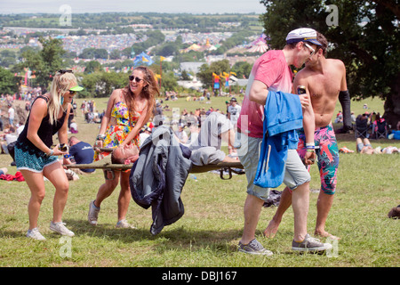 Glastonbury Festival 2013 Festaioli il salvataggio di un amico con una barella vicino al cerchio di pietra Foto Stock