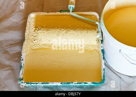 Vassoio verniciato di plastica con il pittore spazzola a rullo e la benna con vernice gialla Foto Stock