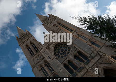 Truro Cathedral facciata prese ad un angolo, mostrando grande abete contro il luminoso cielo blu con nuvole soffici Foto Stock